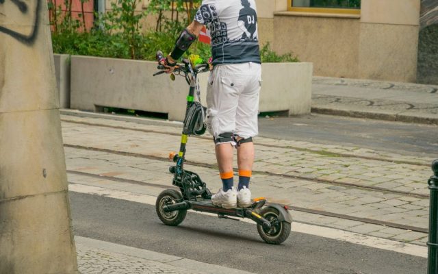 Adult riding an electric scooter on a city street