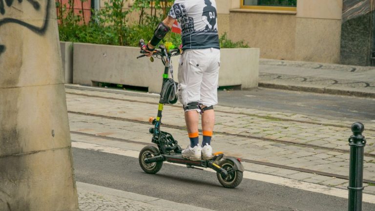 Adult riding an electric scooter on a city street