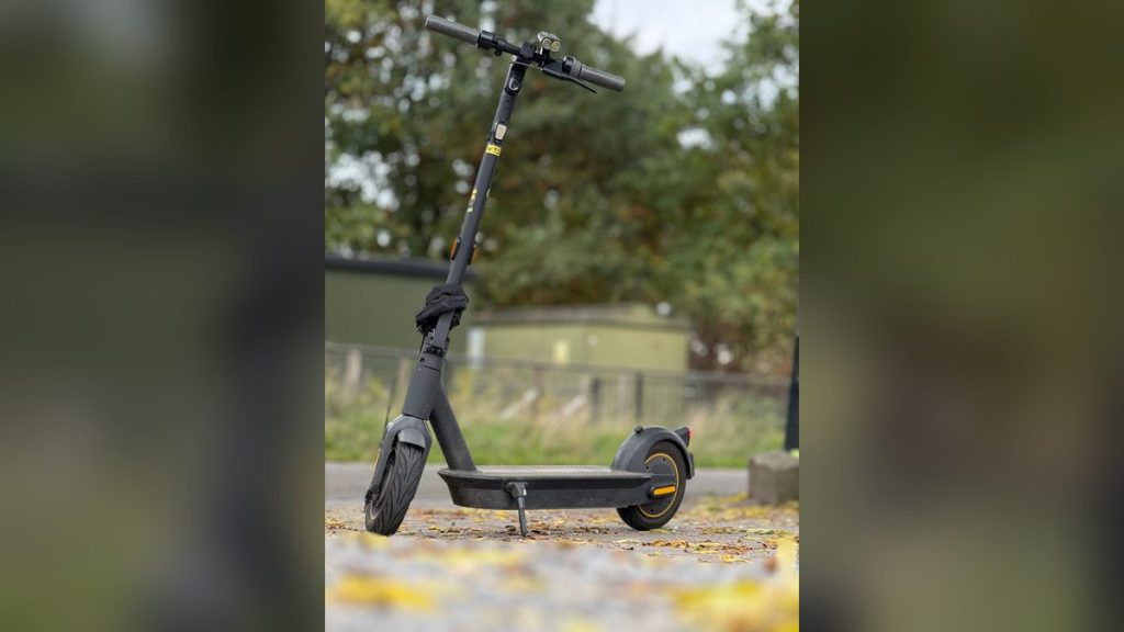 Black electric scooter on a leafy autumn path