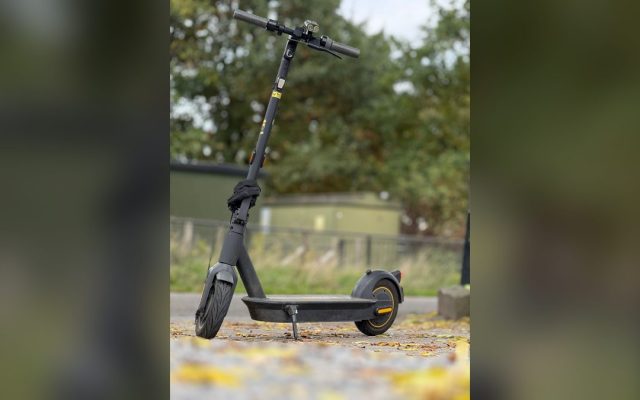 Black electric scooter on a leafy autumn path