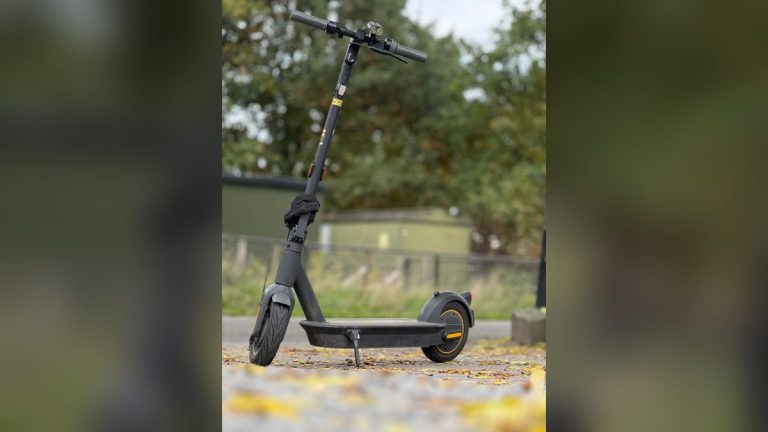 Black electric scooter on a leafy autumn path
