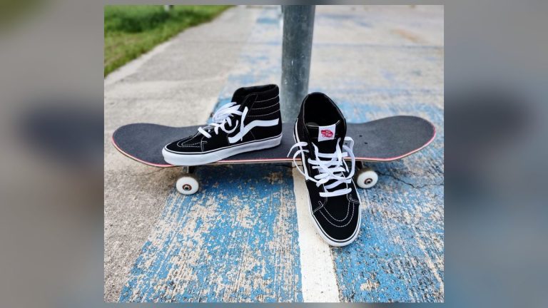 Black sneakers and a skateboard on concrete
