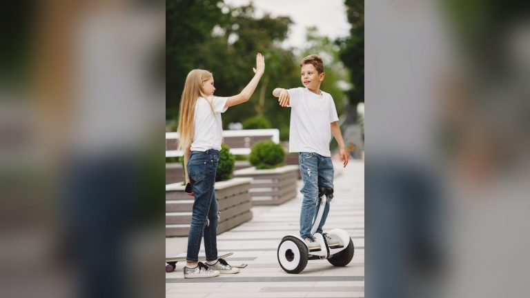 Boy and girl high-fiving on a self-balancing scooter and skateboard