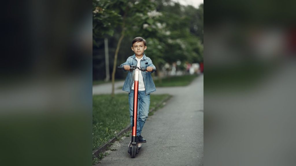 Boy riding a scooter in a park