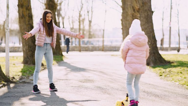 Child riding a kick scooter with her mother