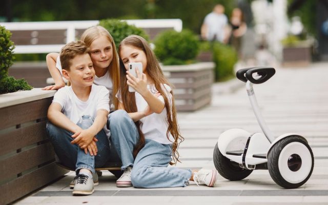 Children taking a selfie with a self-balancing scooter