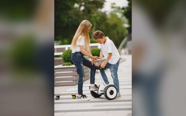 Children with a skateboard and scooter in a park