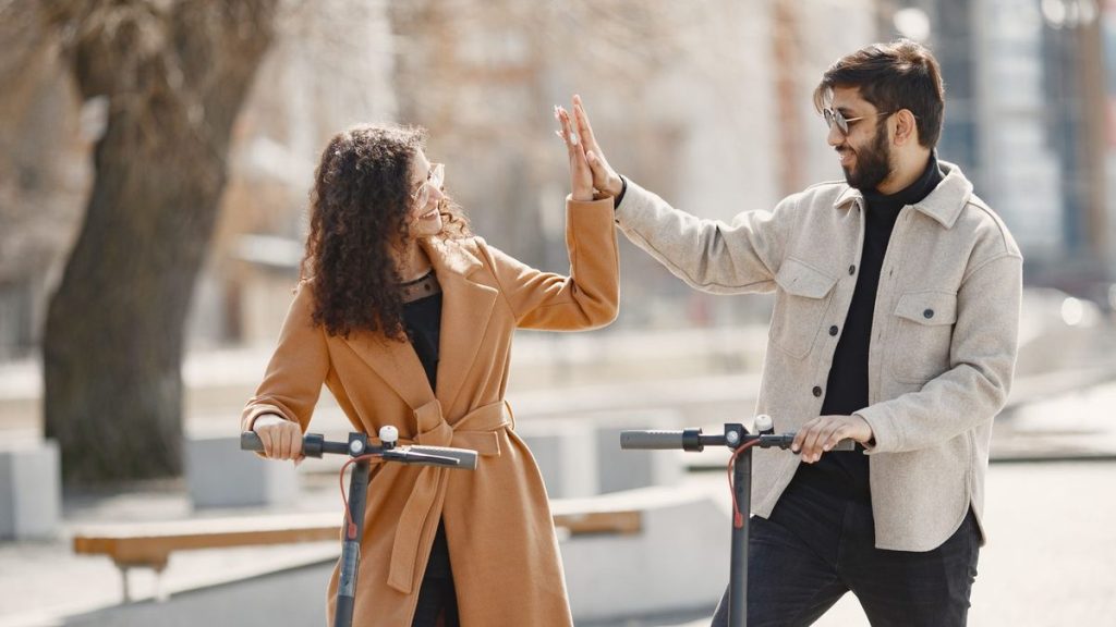 Couple high-fiving while riding electric scooters