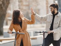 Couple high-fiving while riding electric scooters