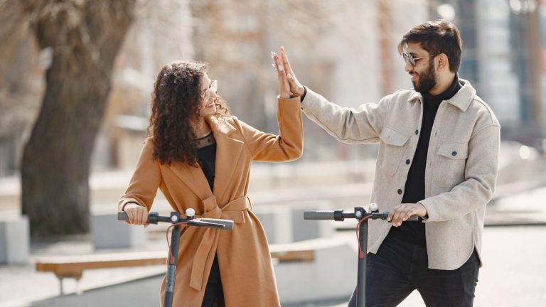 Couple high-fiving while riding electric scooters