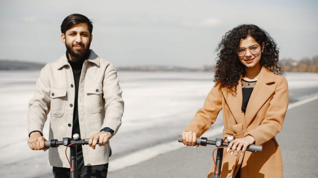 Couple riding e-scooters along a scenic path