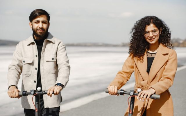 Couple riding e-scooters along a scenic path