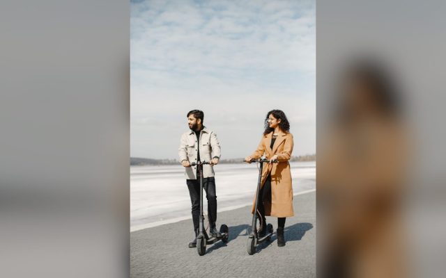 Couple riding e-scooters beside a lake