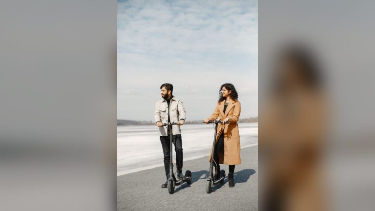 Couple riding e-scooters beside a lake