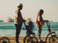 Couple riding electric scooters along a seaside promenade