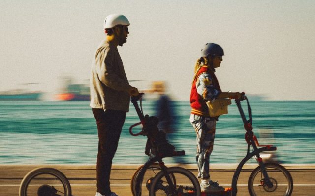 Couple riding electric scooters along a seaside promenade