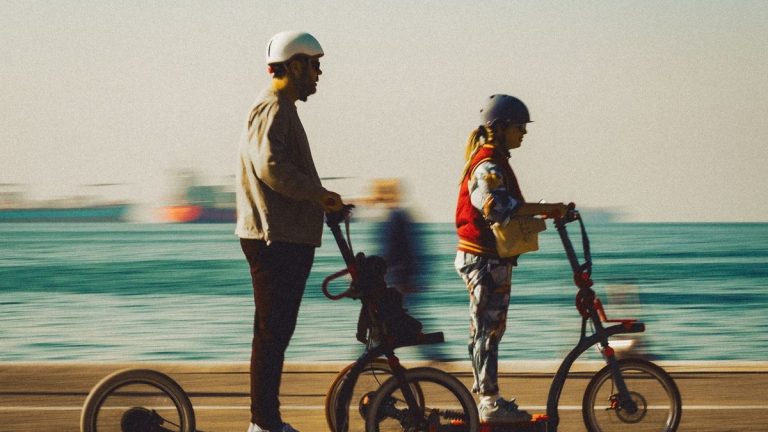 Couple riding electric scooters along a seaside promenade