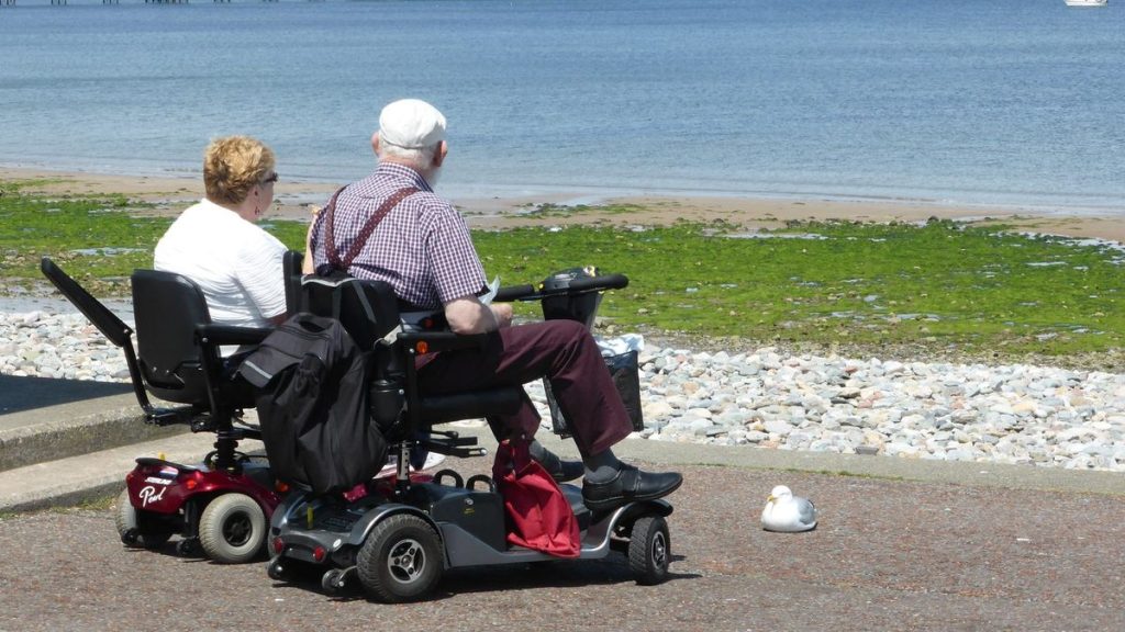 Elderly couple on mobility scooters by the seaside