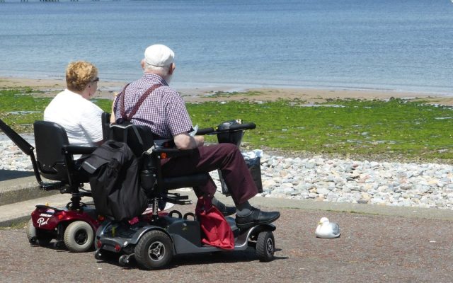 Elderly couple on mobility scooters by the seaside