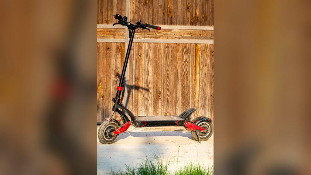 Electric scooter parked in front of a wooden fence