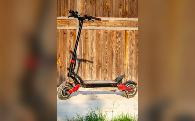 Electric scooter parked in front of a wooden fence