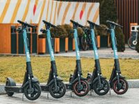 Five electric scooters lined up outdoors