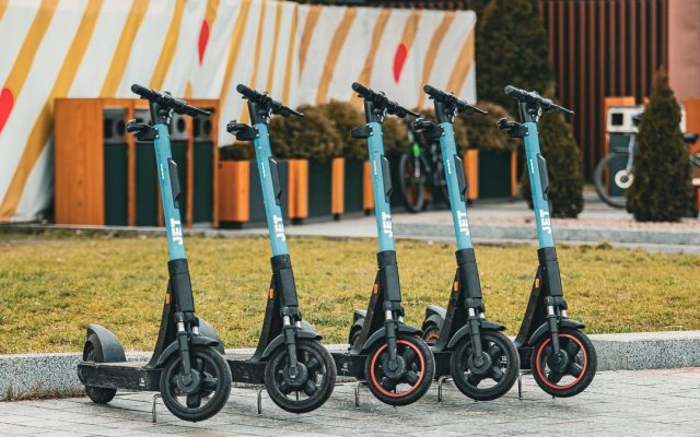 Five electric scooters lined up outdoors