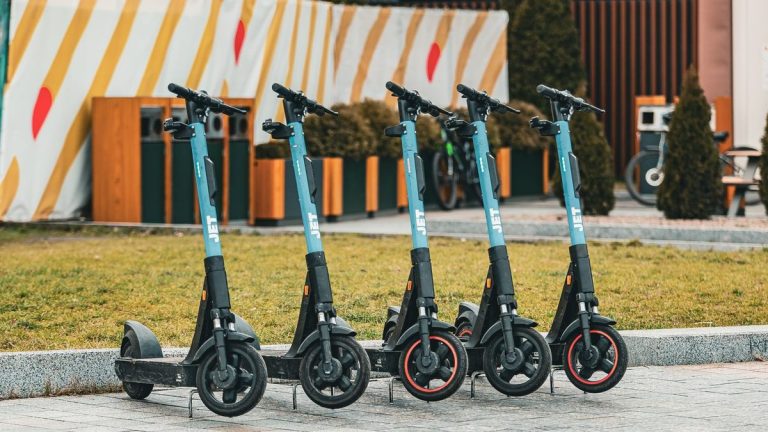 Five electric scooters lined up outdoors