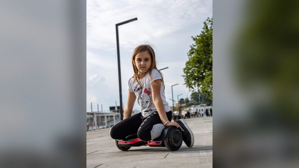 Girl sitting with her hoverboard on the pavement