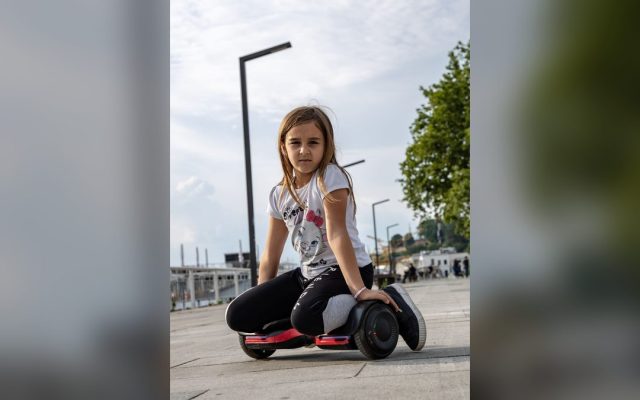 Girl sitting with her hoverboard on the pavement