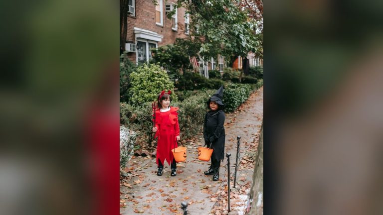 Girls in witch and devil costumes trick-or-treating