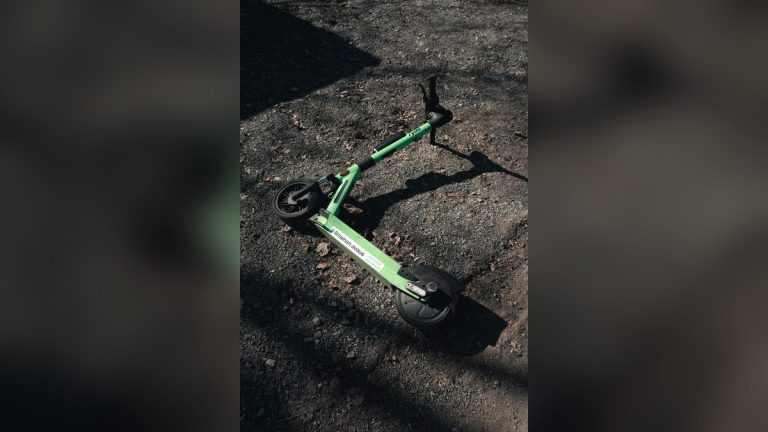 Green electric scooter on a gravel path