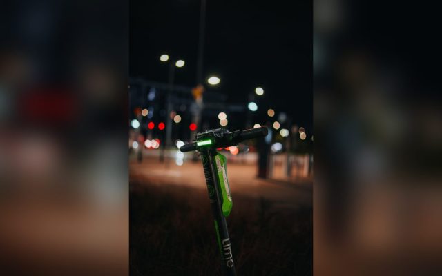 Green electric scooter with its light on at night