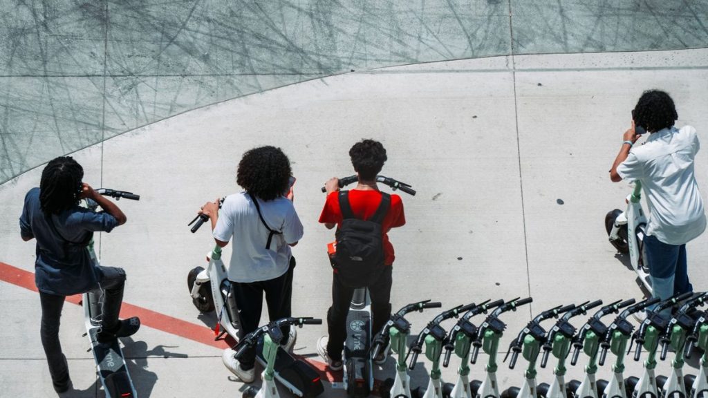 Group of friends with electric scooters on a city pavement