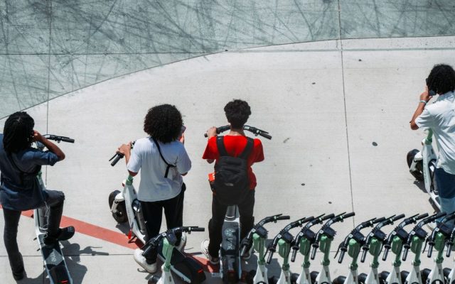Group of friends with electric scooters on a city pavement