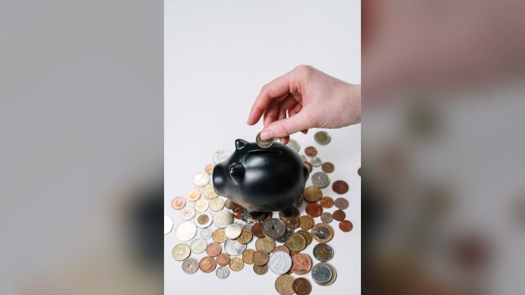 Hand inserting a coin into a piggy bank