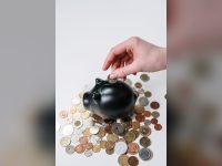 Hand inserting a coin into a piggy bank