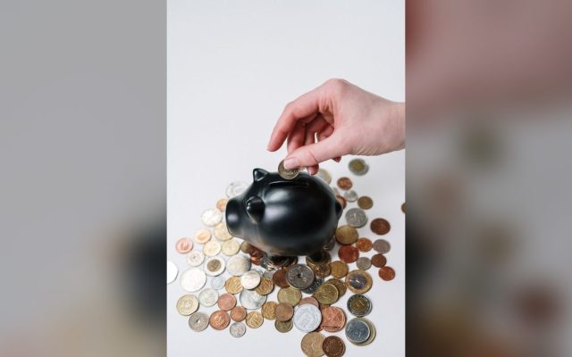 Hand inserting a coin into a piggy bank