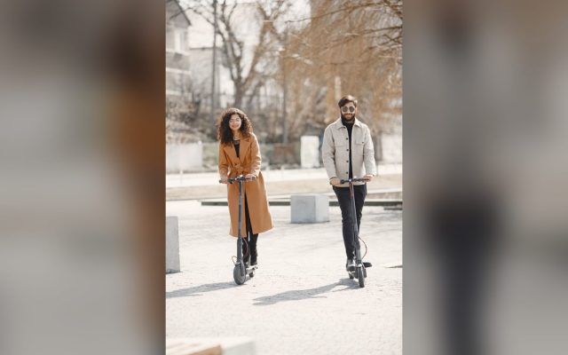 Happy couple riding e-scooters on a sunny day
