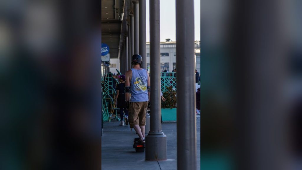 Man in a helmet riding an electric skateboard through the city