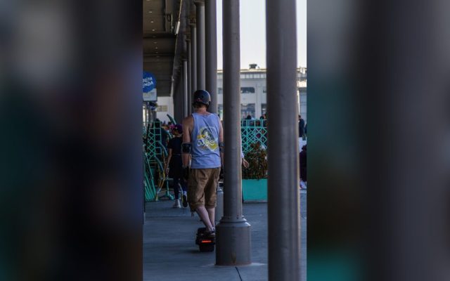Man in a helmet riding an electric skateboard through the city