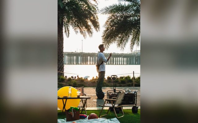 Man on a self-balancing scooter at the waterfront at sunset