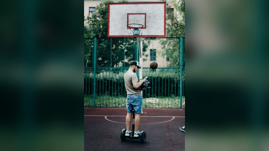 Man riding a self-balancing scooter on a basketball court