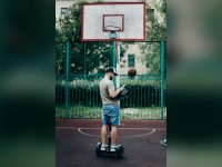 Man riding a self-balancing scooter on a basketball court