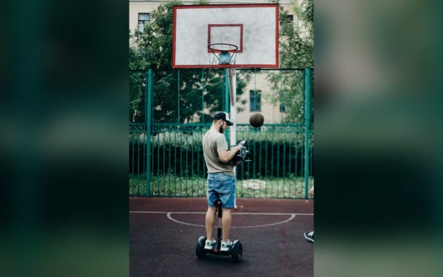 Man riding a self-balancing scooter on a basketball court