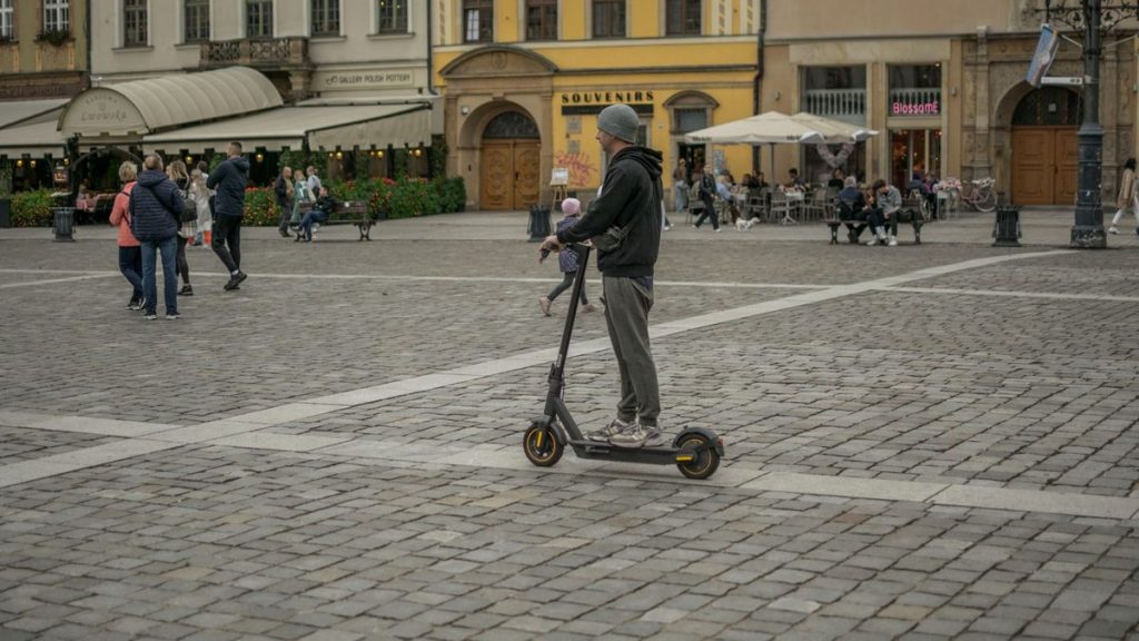 Man riding an e-scooter through a historic city square