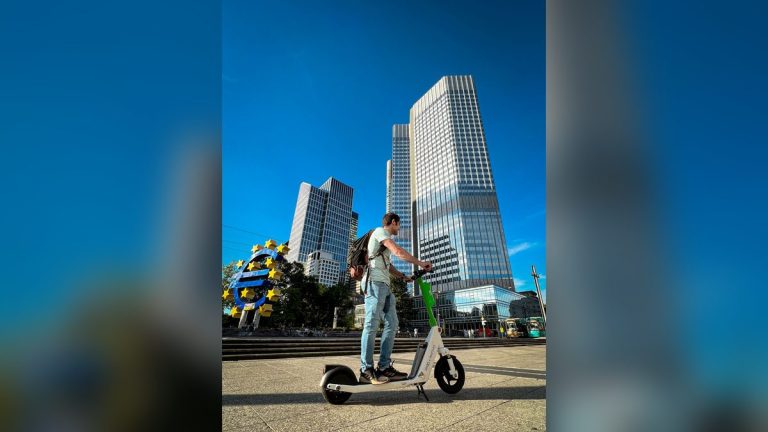 Man riding an electric scooter in front of city skyscrapers