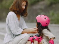 Mother fitting a helmet on her daughter