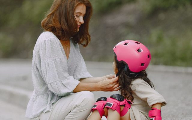 Mother fitting a helmet on her daughter
