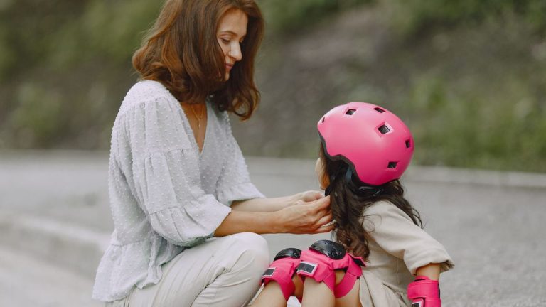 Mother fitting a helmet on her daughter